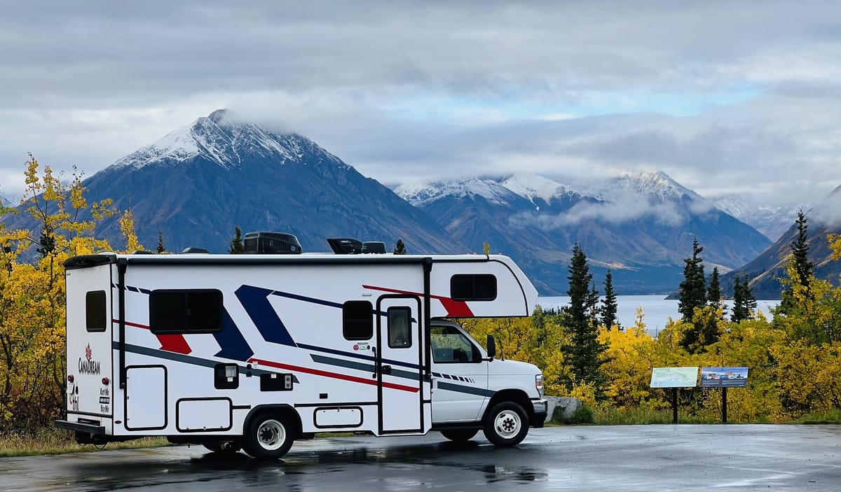 CanaDream motorhome by a lake with snow-capped mountains and autumn colours in Canada