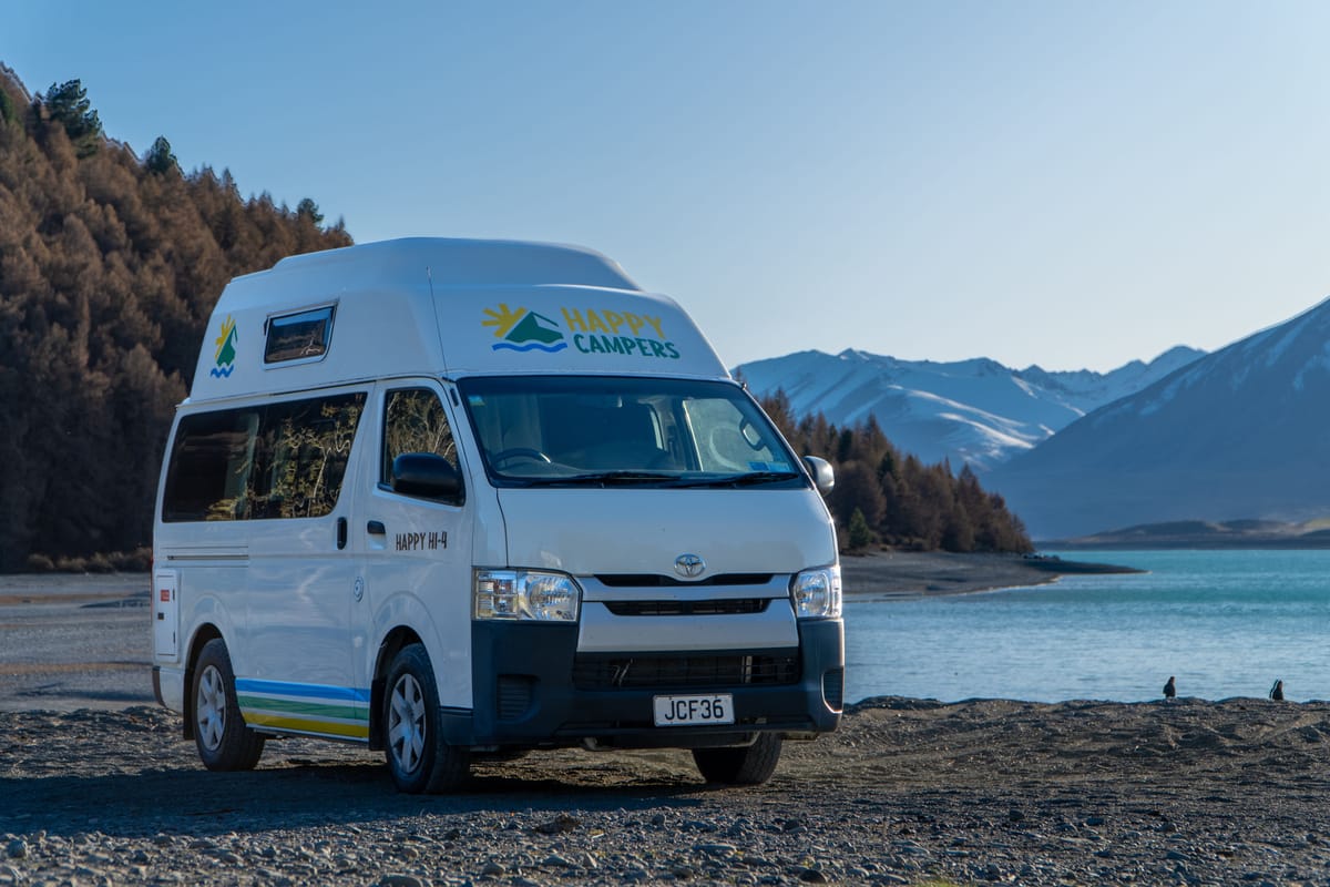 Happy Campers hi-top campervan parked by a mountain lake in New Zealand