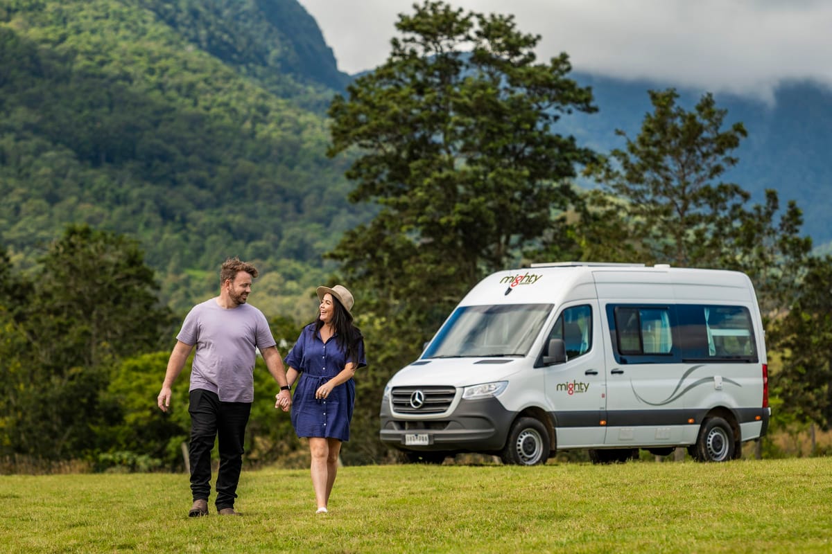 Couple walking beside a Mighty campervan in the green Scenic Rim, Australia